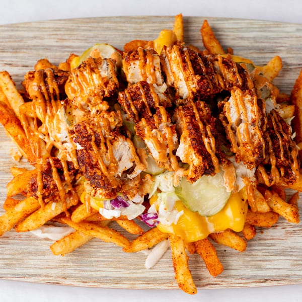 Cluck & Smash loaded fries with crispy fried chicken, cheese sauce, pickles, and coleslaw.